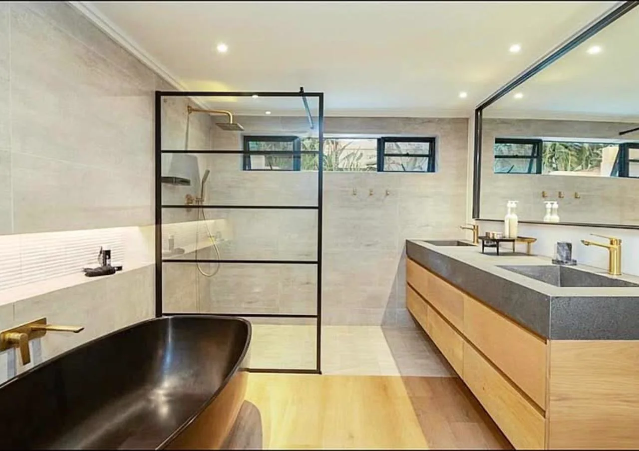 Wide view of a luxury bathroom with a black bath, walk-in shower and timber double vanity