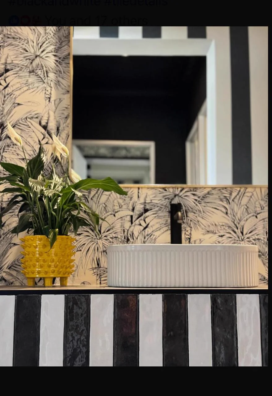 Detailed view of a striped bathroom vanity, botanical wallpaper and illuminated mirror