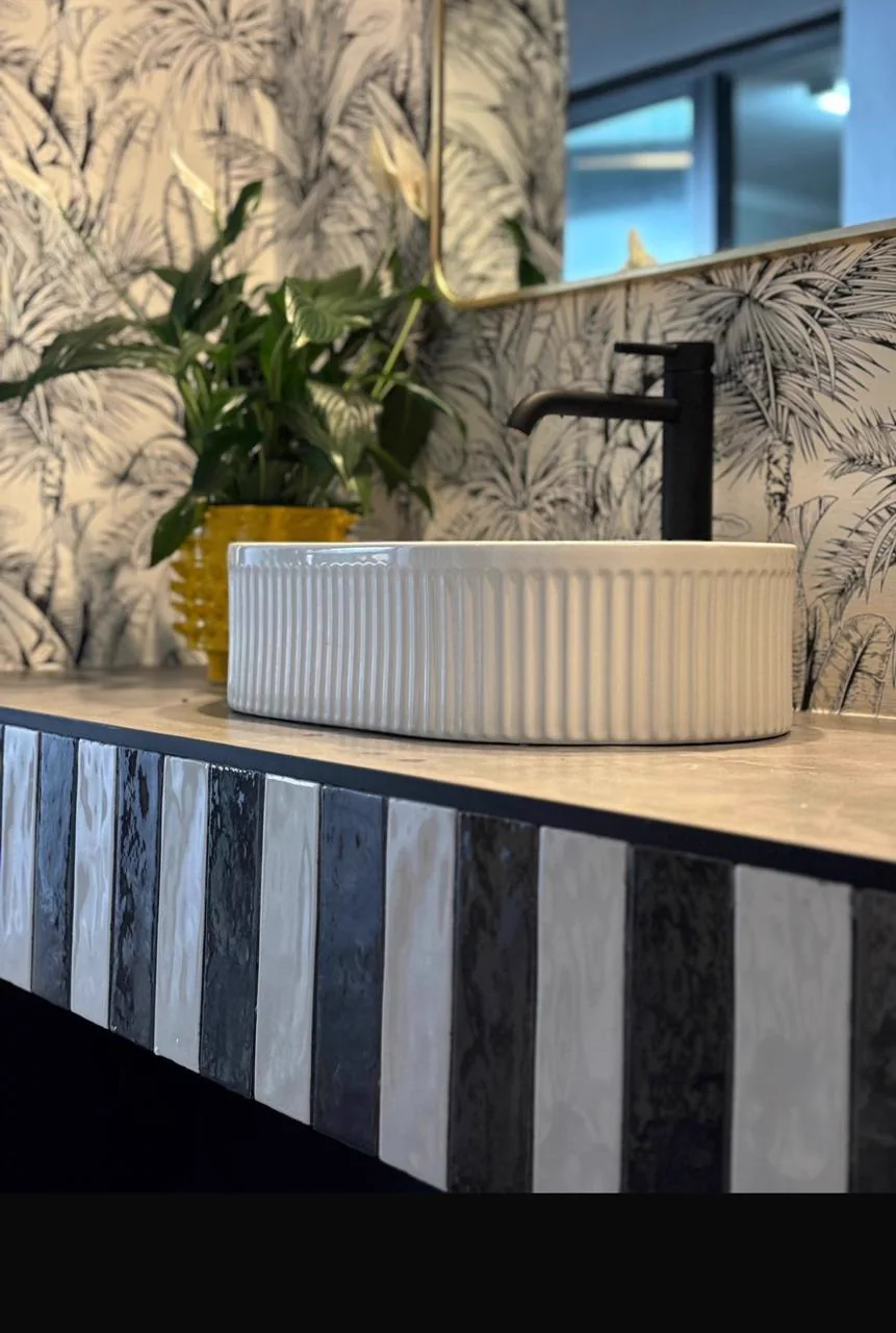 Fluted vessel basin on a striped custom vanity against botanical wallpaper