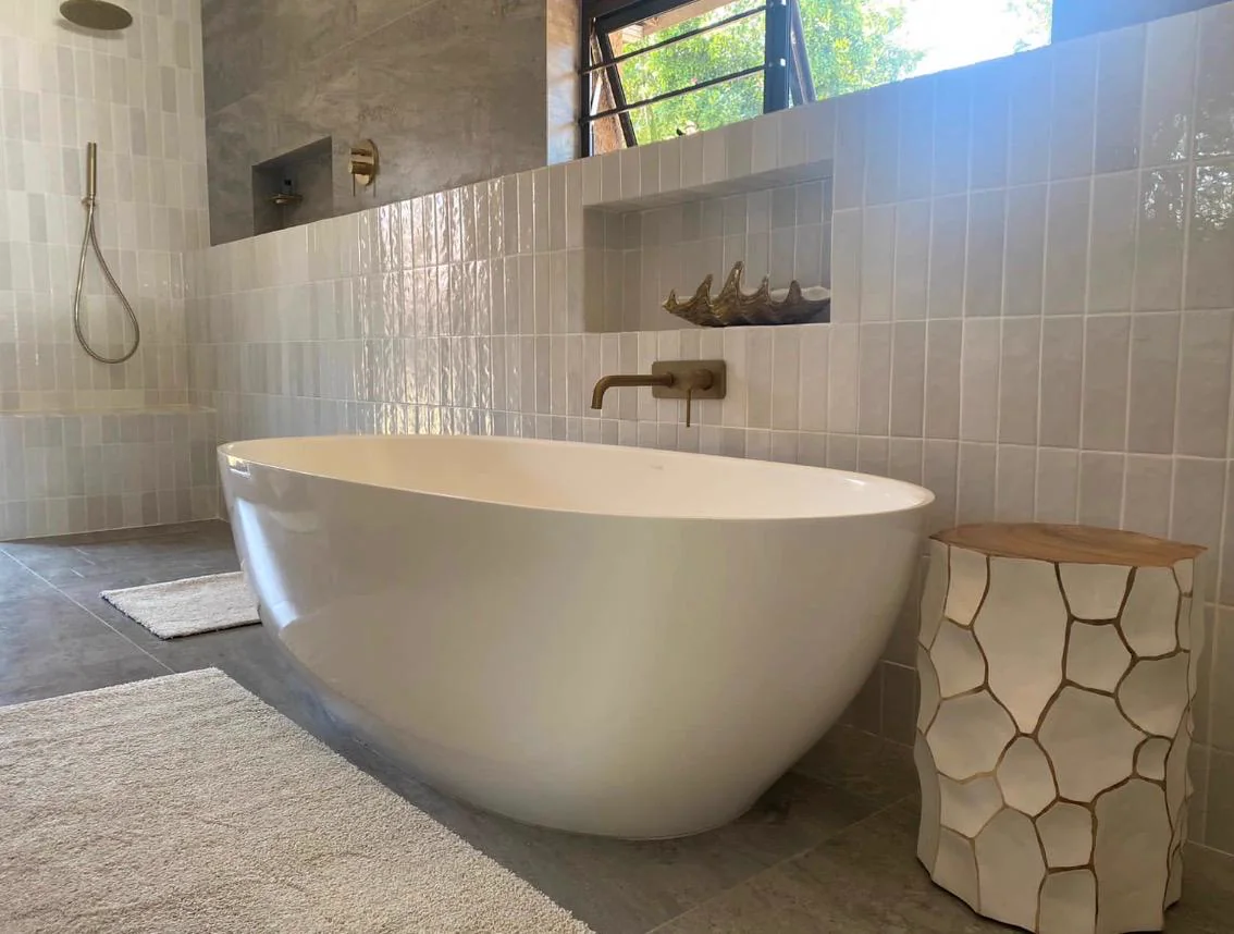 Freestanding white bath with a wall-mounted tap and textured feature wall
