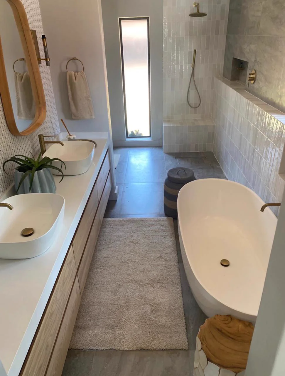 Completed narrow bathroom with a timber vanity, freestanding bath and natural light