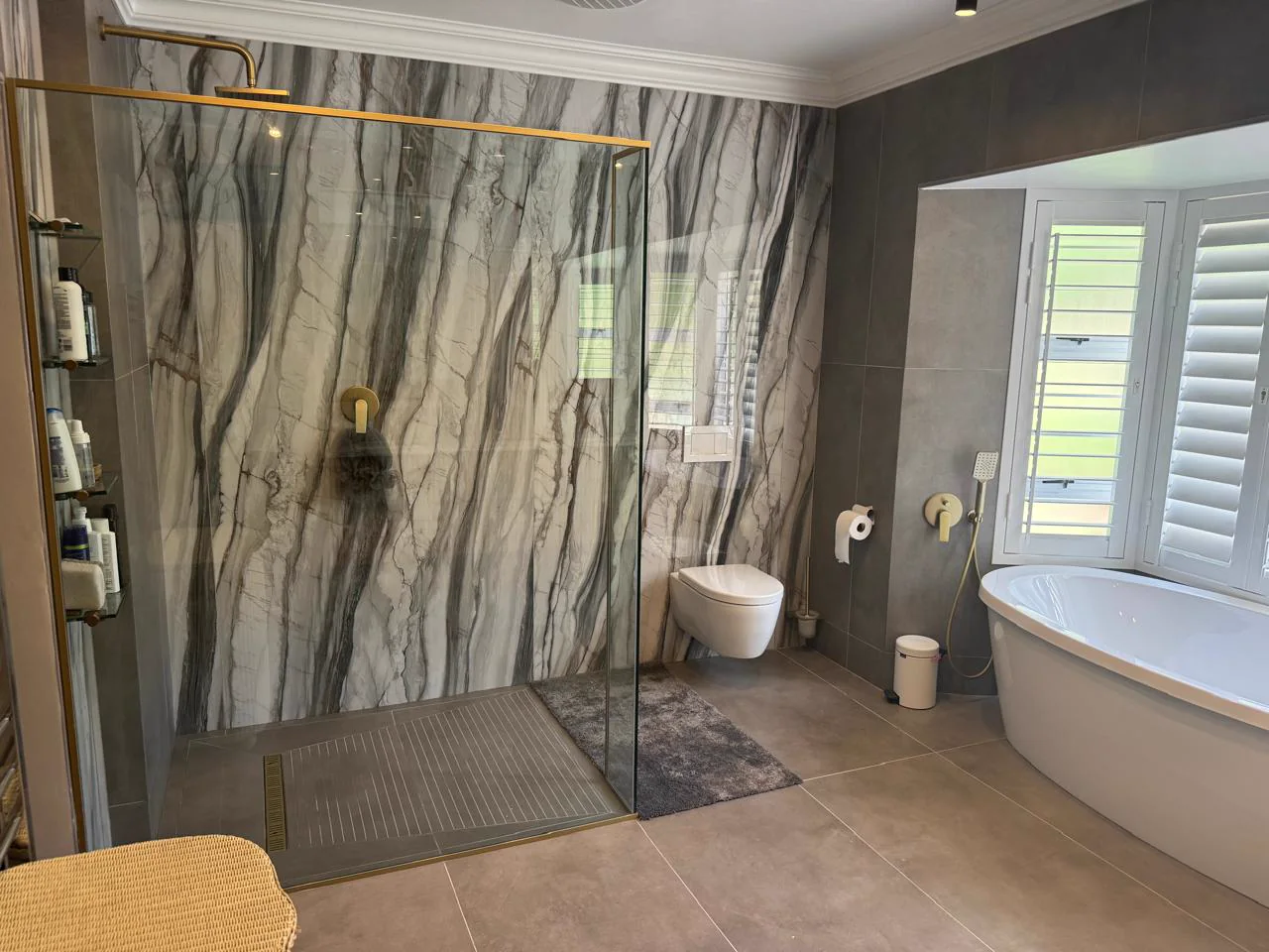 Spacious completed bathroom with marble-look wall tiles, walk-in shower and freestanding bath
